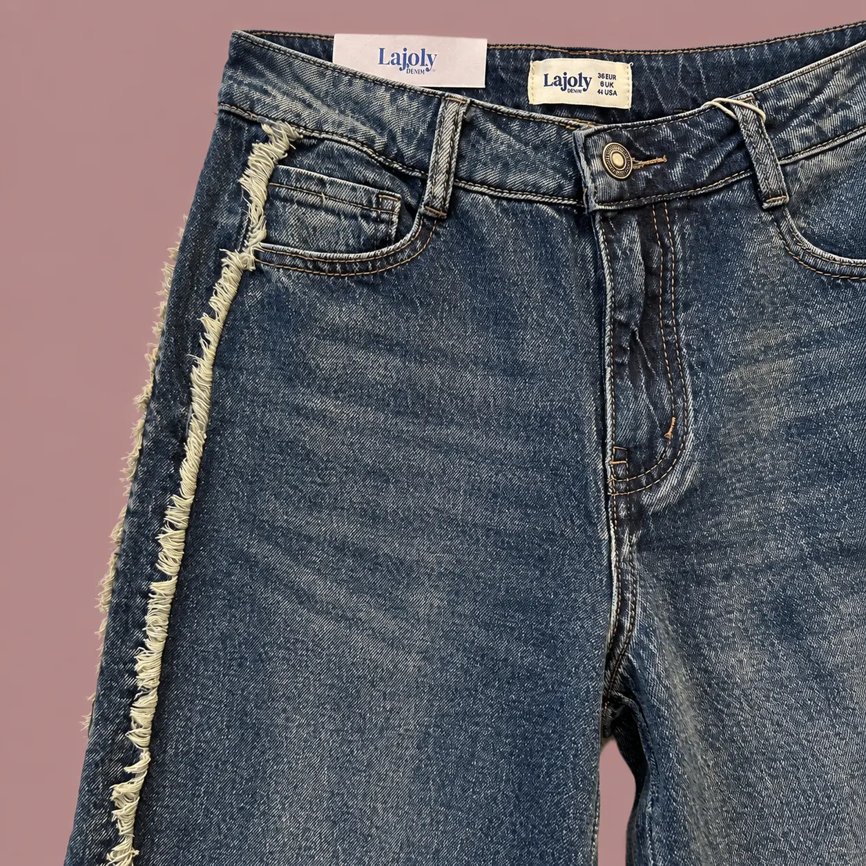 Detalhe de jeans azul-escuro em fundo rosa-1.webp